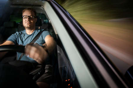 Handsome young driver driving hic car fast yet safely on the road