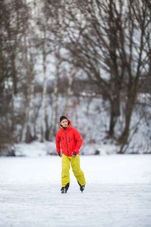 Young man ice skating outdoors on a pond on a freezing winter dayの写真素材