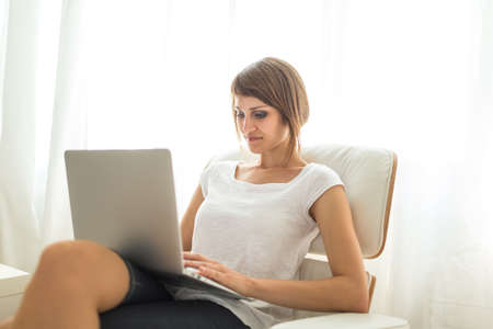 Young woman with laptop in her comfortable apartmentの写真素材