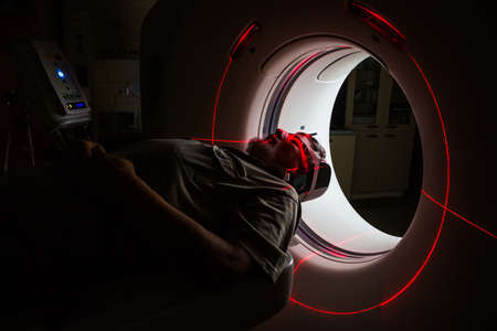 Senior man going through a Computerized Axial Tomography (CAT) Scan medical test/examination in a modern hospital (color toned image; shallow DOF)の写真素材