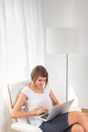 Young woman with laptop in her comfortable apartmentの写真素材