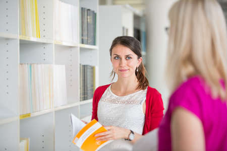 Pretty young college student in a library (shallow DOF; color toned image)の写真素材