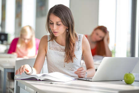 Pretty young college student in a library (shallow DOF; color toned image)の写真素材