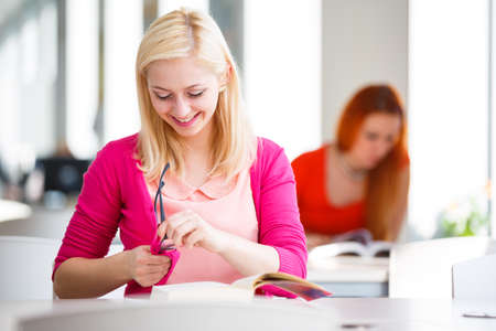 Pretty young college student in a library (shallow DOF; color toned image)の写真素材