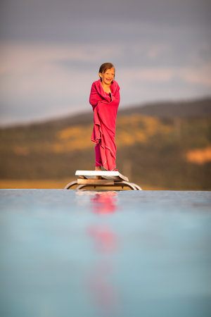 Little girl on a pool's edge, learning to swim and dive. Swimming with kids. Healthy sport activity for children. Sun protection. Water fun.の写真素材