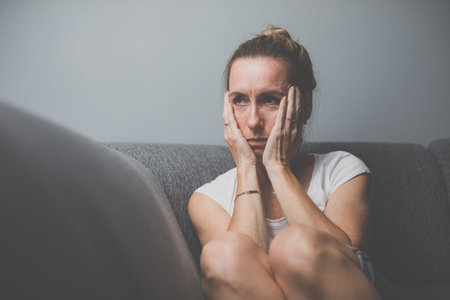 Depressed mid-aged woman at home feeling sad, lonely, anxious (color toned image)の写真素材