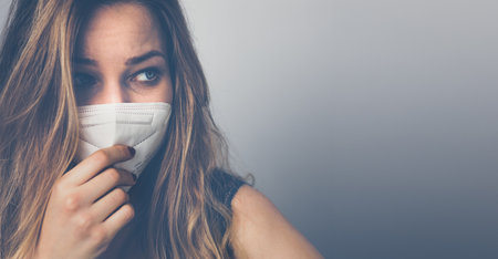 Young woman wearing a face mask during  and flu outbreak. Virus and illness protection, home quarantine.の写真素材