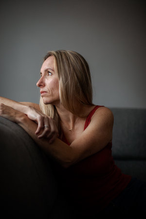 Depressed mid-aged woman at home feeling sad, lonely, anxious (color toned image)の写真素材