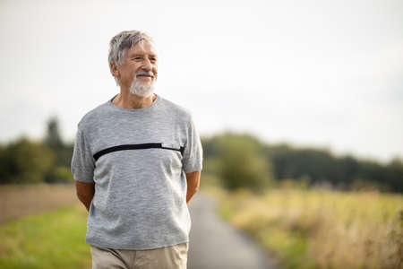 Happy senior man walking outdoors on a warm summer dayの写真素材