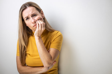 Mid-aged woman touching her cheek/mouth with painful expression because of toothache/dental issueの写真素材