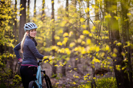 Pretty, young woman with her mountain bike going for a ride past the city limits, getting her dose of daily cardioの写真素材