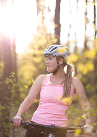 Pretty, young woman with her mountain bike going for a ride past the city limits, getting her dose of daily cardioの写真素材