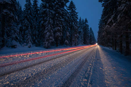 Cars on a snowy winter road amid forests - using its four wheel drive capacities to get through the snow - motion blurred imageの写真素材