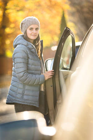Pretty young woman by her car ready for her daily commute to workの写真素材