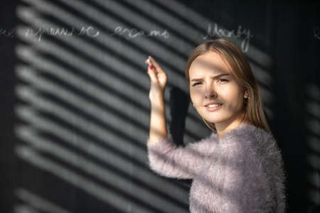 Pretty, young female student in front of a blackboard during classの写真素材
