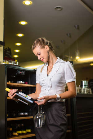 Cute female sommelier, wine waiter choosing the right wine to go well with food in a restaurantの写真素材