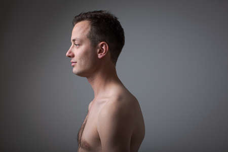 Dark (low key) portrait of a, handsome young man on grey backgroundの写真素材