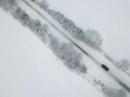 Aerial view of a car on winter road in the forest. Winter landscape countryside. Aerial photography...
