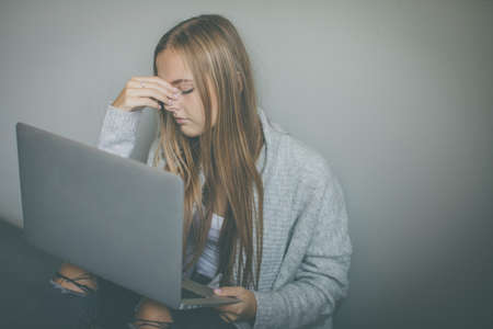 Pretty, young woman with her laptop studying for an exam / workingの写真素材