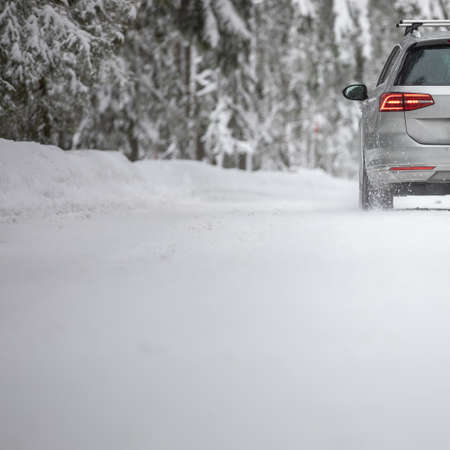 Car on a snowy winter road amid forests - using its four wheel drive capacities to get through the snowの写真素材