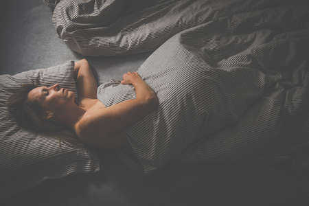Pretty, middle-aged woman using her tablet computer before sleep in bed in the eveningの写真素材