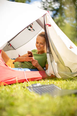 Cell phone charging with a solar charger in a tent during an outdoor tripの写真素材
