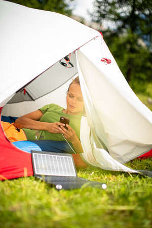 Cell phone charging with a solar charger in a tent during an outdoor tripの写真素材
