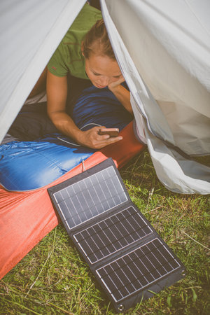 Cell phone charging with a solar charger in a tent during an outdoor tripの写真素材