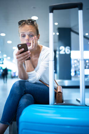 Young woman with her luggage at an international airport, before going through the check-in and the security check before her flightの写真素材