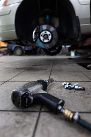 Car in a garage for maintenance, oil/tyre change (shallow DOF; color toned image)