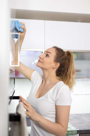 Young woman polishes a modern bright kitchenの写真素材