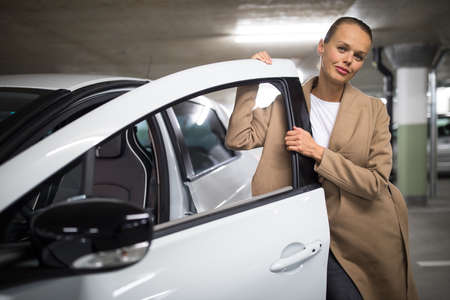 Underground parking/garage (shallow DOF; color toned image) - young woman with her car in the underground parkingの写真素材