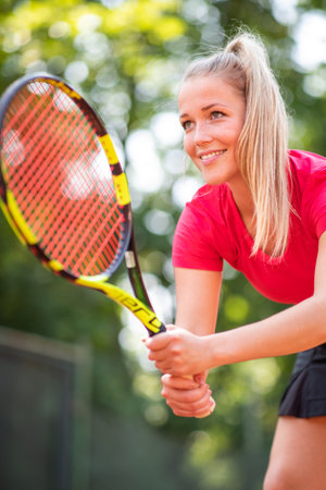 Pretty, young woman tennis player playing on a clay court. Healthy active lifestyle conceptの写真素材