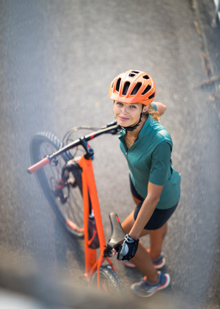 Pretty, young woman with her mountain bike going for a ride past the city limits, getting the daily cardio doseの写真素材