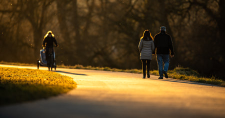 People walking along a river in a park on a lovely winter eveningの写真素材