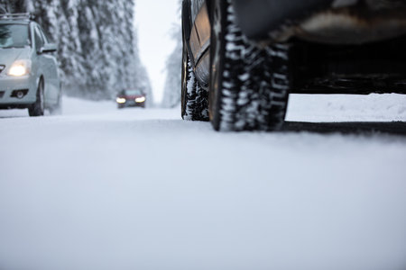 Car on a snowy winter road amid forests - using its four wheel drive capacities to get through the snowの写真素材