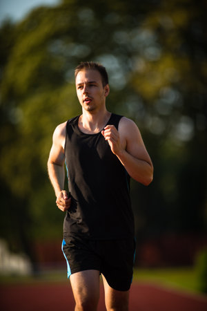 Handsome young runner jogging outdoors on a lovely summer eveningの写真素材