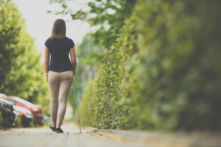 Blind woman walking on city streets, using her white caneの写真素材