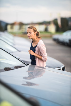Pretty, young woman looking at cars, picking the model she would buy.の写真素材