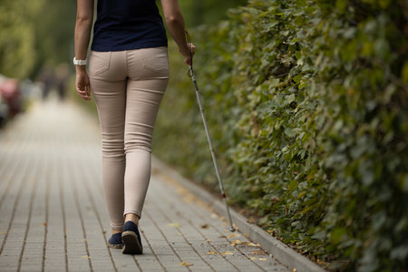 Blind woman walking on city streets, using her white caneの写真素材