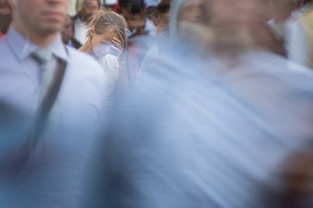 Crowd of people walking on city street - motion blurred image with unrecognizable faces - Young woman standing still, feeling down, depressedの写真素材
