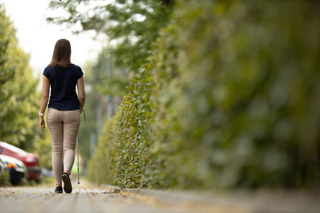 Blind woman walking on city streets, using her white caneの写真素材