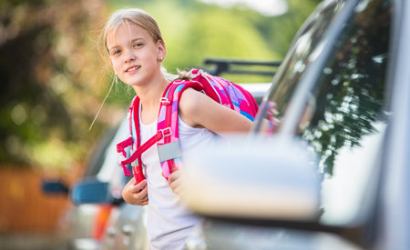 Cute little girl going home from school, looking well before crossing the streetの写真素材