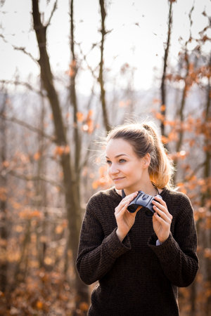 Young woman with binoculars outdoors on fall day. Enjoying the outdoors.の写真素材