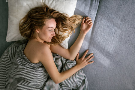 Pretty, young woman sleeping in her bed late in the morning on a weekend - compensating for the lack...