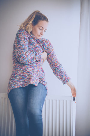 Cold, depressed middle-aged woman at home feeling sad, lonely, anxious about energy prices going up (color toned image)の写真素材