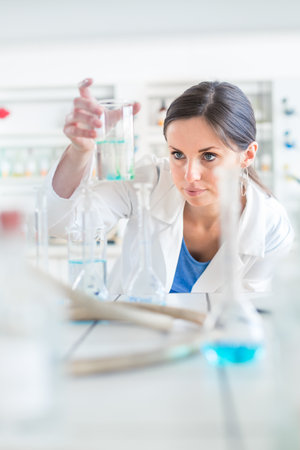 Young, female researcher carrying out experiments in a lab (shallow DOF; color toned image)の写真素材