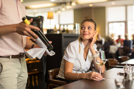 Cute female restaurant customer with wine waiter choosing the right wine for her to go well with the foodの写真素材