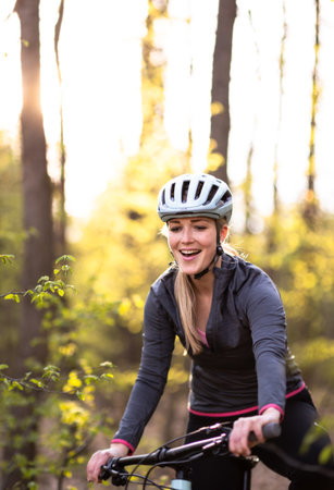Pretty, young woman with her mountain bike going for a ride past the city limits, getting her dose of daily cardioの写真素材