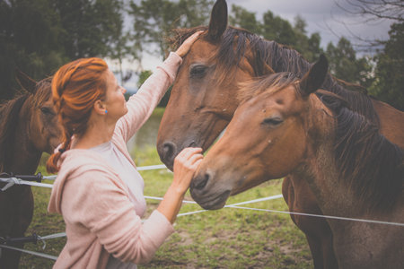 Pretty, young, redhead woman with her lovely horse, during her favorite leisure